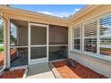 Close-up of a cozy screened porch with brick flooring, shuttered windows, and outdoor seating at 8404 Fishhawk Ave, New Port Richey, FL 34653