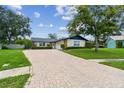 Charming home featuring a brick driveway, lush landscaping, and a well-maintained lawn at 1071 Lexington Ct, Largo, FL 33771