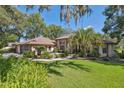 Inviting exterior with a well-manicured lawn and lush landscaping surrounding the pink stucco and brick home at 12295 Clarendon Ct, Spring Hill, FL 34609