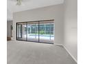 Bright living room with neutral carpet and sliding glass doors leading to a screened pool area at 13125 Jessica Dr, Spring Hill, FL 34609