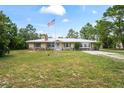 This charming ranch-style home offers a metal roof, stone accents, and a lovely front lawn with an American flag at 13345 Convent Garden Rd, Brooksville, FL 34613
