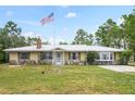 Ranch home showcasing stone accents, a metal roof, an American flag, and a well-manicured lawn at 13345 Convent Garden Rd, Brooksville, FL 34613