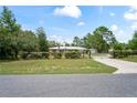 Inviting ranch-style home with a gated driveway, mature trees, and beautifully maintained landscaping at 13345 Convent Garden Rd, Brooksville, FL 34613