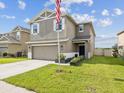 A two-story home has a two-car garage, a manicured lawn, and a covered front entrance with an American flag at 14000 Lugano Ct, Hudson, FL 34669