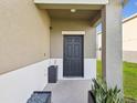 Inviting covered front porch featuring a black door and sleek potted plants at 14000 Lugano Ct, Hudson, FL 34669