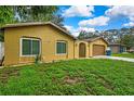A yellow single-story home with a two-car garage and a well-maintained front yard at 2169 Danforth Rd, Spring Hill, FL 34608