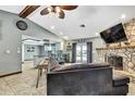Bright living area showcasing the stone fireplace, ceiling fan, and a view to the kitchen at 364 Waterfall Dr, Spring Hill, FL 34608