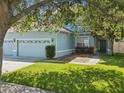 Inviting exterior showcasing a three-car garage, lush lawn, and well-maintained landscaping at 4481 Birchfield Loop, Spring Hill, FL 34609
