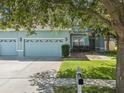 Charming light-blue home featuring a three-car garage and well-maintained lawn at 4481 Birchfield Loop, Spring Hill, FL 34609