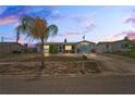 Exterior shot of a one-story house with a palm tree in the front yard, set against a colorful sky at dusk at 5321 Mosaic Dr, Holiday, FL 34690