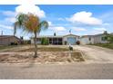 Single-story house with a well-manicured lawn, light blue garage door, and a lush palm tree in the front yard at 5321 Mosaic Dr, Holiday, FL 34690