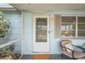 Enclosed porch featuring a cozy chair, potted plants, and a stylish white door at 5321 Mosaic Dr, Holiday, FL 34690
