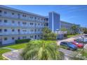 Exterior daytime shot of a multi-story light blue condo building with beautiful landscaping, a parking lot, and outdoor seating at 5555 Gulf Blvd # 315, St Pete Beach, FL 33706