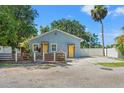 Cozy light blue one-story house featuring a fenced front yard and yellow door detail at 5724 Casson Ave, New Port Richey, FL 34652