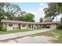A charming, well-maintained exterior with a long driveway and a garage, nestled amongst mature trees at 6019 Wyoming Ave, New Port Richey, FL 34653