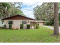 A well-maintained home with a lush front lawn, mature trees, and beautiful landscaping at 6019 Wyoming Ave, New Port Richey, FL 34653
