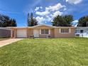 Charming single-story home featuring a well-maintained lawn and attached garage under a sunny blue sky at 6341 Hyperion Dr, Port Richey, FL 34668
