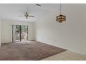 Open living area featuring a ceiling fan, unique light fixture, and sliding door to backyard at 7122 Barclay Ave # B, Spring Hill, FL 34609