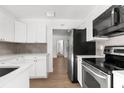 Bright kitchen featuring white cabinets, stainless steel appliances, and hardwood flooring at 7192 Catalina St, Spring Hill, FL 34606