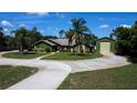Inviting single-story home with a circular driveway, lush lawn, mature landscaping, and detached garage at 7550 Jomel Dr, Weeki Wachee, FL 34607