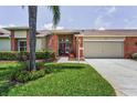 Charming single-story home with a red front door, well-manicured lawn, and an attached two-car garage at 1009 Almondwood Dr, Trinity, FL 34655