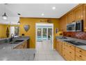 Well-lit kitchen with granite countertops, wooden cabinets, and modern stainless steel appliances at 1430 Rosetree Ct, Clearwater, FL 33764