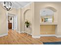 Bright foyer featuring wood flooring, arched doorways, and a decorative foyer table at 15004 Middle Fairway Dr, Spring Hill, FL 34609