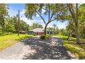 Well-maintained single-story home with mature trees and a circular driveway leading to the three-car garage at 22850 Skyview Cir, Brooksville, FL 34602