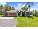 Inviting single-story home with a neatly kept lawn, a mature palm tree, and a three-car garage at 22850 Skyview Cir, Brooksville, FL 34602