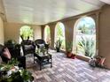 Inviting covered patio featuring brick flooring, comfortable wicker furniture and lush potted plants at 3447 Paloma Dr, Holiday, FL 34690