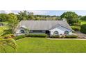 Beautiful one-story home with manicured lawn, garden beds, and arched windows; view of the lake in the background at 8522 Cranes Roost Dr, New Port Richey, FL 34654