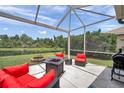 Cozy screened patio with comfortable seating, fire pit, grill, and a peaceful view of the pond at 9309 Edistro Pl, New Port Richey, FL 34654