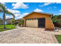 Home exterior featuring an attached garage, brick paver driveway and manicured landscaping at 10924 Archway Ave, Hudson, FL 34667