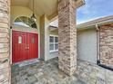 Charming front entrance with a red double door, brick pillar, and decorative hanging light fixture at 10060 Chip Ln, New Port Richey, FL 34654