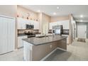Spacious kitchen with granite countertops, white cabinetry, stainless steel appliances, and a large center island at 11395 Lavender Loop, Spring Hill, FL 34609