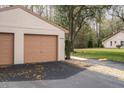 Exterior view of the two-car garage with black asphalt driveway of villa in Sugar Creek community at 13134 Cypress Hill Dr, Hudson, FL 34669