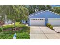Charming blue house with a two-car garage, well-manicured lawn, and beautiful landscaping at 13321 Norman Cir, Hudson, FL 34669