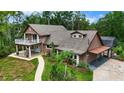 Aerial view of a two-story home with lush greenery, balcony, and an attached carport at 2202 Amity Ct, New Port Richey, FL 34655