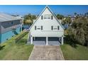 A-frame stilt home with light green siding, black shutters, and covered parking area at ground level at 3363 Poinsettia Dr, Hernando Beach, FL 34607