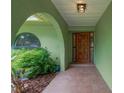 Arched entryway with wooden front door, tiled floor, and lush landscaping at 5021 Bridgeport Dr, Safety Harbor, FL 34695