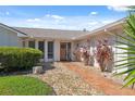 Inviting home entrance with a decorative wreath, a stone pathway, and lush landscaping at 5348 Lawrence Ln, New Port Richey, FL 34652