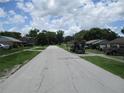 Quiet residential street lined with single-Gathering homes and mature trees under a partly cloudy sky at 6030 17Th St, Zephyrhills, FL 33542