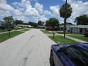 Residential street featuring single-Gathering homes, manicured lawns, and mature trees under a sunny sky at 6030 17Th St, Zephyrhills, FL 33542