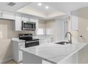 Modern kitchen with white cabinets, quartz counters, and stainless steel appliances with large breakfast bar at 6509 Pine Meadows Dr, Spring Hill, FL 34606