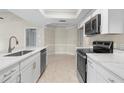 Modern kitchen featuring white cabinetry, stainless steel appliances, and a breakfast bar overlooking the dining area at 6509 Pine Meadows Dr, Spring Hill, FL 34606