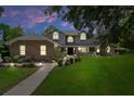 Charming two-story home with a brick facade, front porch, and manicured front yard at dusk at 7268 Crystal Spring Run, Weeki Wachee, FL 34607