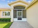 Home's inviting screened front porch, framed by manicured landscaping, with brick-paved entry at 8401 Pavilion Dr, Hudson, FL 34667