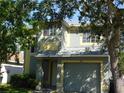 Two-story home featuring a gray and yellow exterior, a front yard with mature trees, and a driveway leading to an attached garage at 846 Burlwood St, Brandon, FL 33511