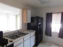 Functional kitchen with stainless steel sink, neutral countertops, wood cabinets, and black refrigerator at 846 Burlwood St, Brandon, FL 33511
