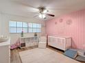 Cozy Bedroom with pink accent wall, white crib, and ceiling fan at 9425 Sterling Ln, Port Richey, FL 34668